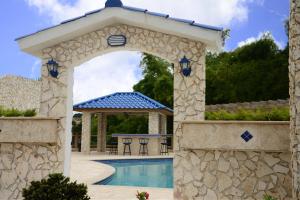 a stone archway over a swimming pool with a gazebo at Hacienda Margarita in Barranquitas