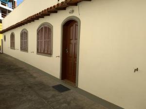 ein weißes Gebäude mit brauner Tür und Fenstern in der Unterkunft Casa na orla da Praia do Forte in Cabo Frio