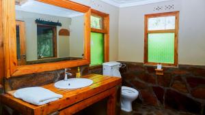 a bathroom with a sink and a mirror and a toilet at Rushaga Gorilla Lodge in Bugambira