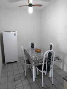 a table with chairs and a refrigerator in a kitchen at Casa Praia do Forte in Cabo Frio