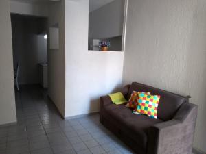 a brown couch with two colorful pillows in a room at Casa Praia do Forte in Cabo Frio