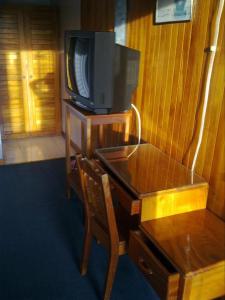 een tv bovenop een houten tafel met een houten bureau bij Hotel Naralit in Tilarán