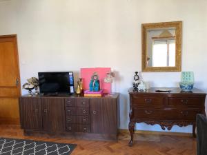 a living room with a tv on a dresser and a mirror at Sunset view apartment in Figueira da Foz