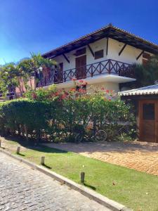 una casa blanca con arbustos y una calle en Cond Solar Lagoa dos Pássaros en Praia do Forte