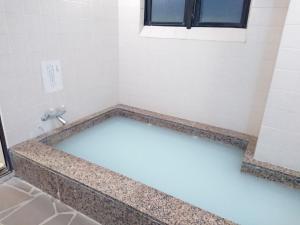 a bathroom with a white wall and a sink at Hotel Crown Hills Imabari in Imabari