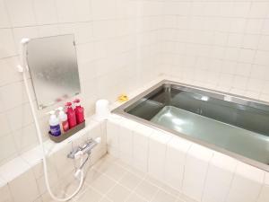 a bathroom with a bath tub and a mirror at Hotel Crown Hills Imabari in Imabari