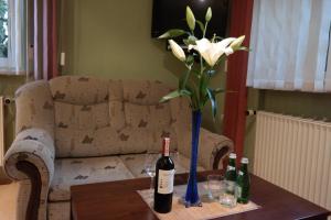 a bottle of wine sitting on a couch next to a vase of flowers at VillaMirage in Tarnowskie Góry