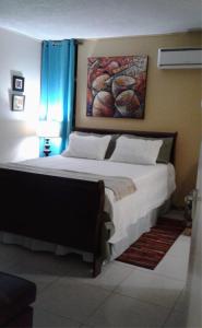 a bedroom with a large bed with a painting on the wall at The Artist Place at Oxford New Kingston in Kingston