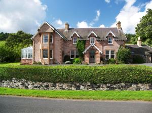 a large brick house with a green hedge at Clint Lodge in Melrose