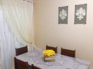 a dining room table with a bowl of yellow flowers on it at Recanto da Dani in Penha