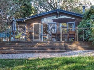 a log cabin with a table and an umbrella at Lark Cottage in Burrawang