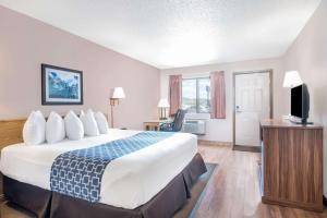 a hotel room with a large bed and a television at Days Inn by Wyndham Spearfish in Spearfish