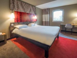 ein großes Bett in einem Zimmer mit einem roten Teppich in der Unterkunft ibis Rouen Centre Champ de Mars in Rouen