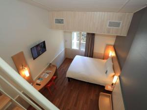 een hotelkamer met een bed en een bureau en een bed sidx sidx sidx sidx bij ibis Aurillac in Aurillac