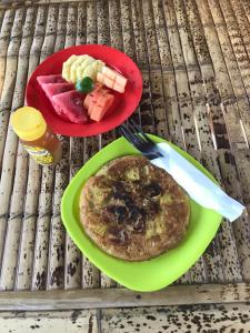 a table with two plates of pancakes and fruit at Meno Madia Bungalows in Gili Meno