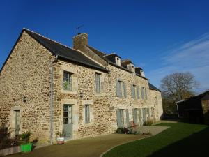 un antiguo edificio de ladrillo con un patio de césped en les jardins de la Matz, en Plouër-sur-Rance