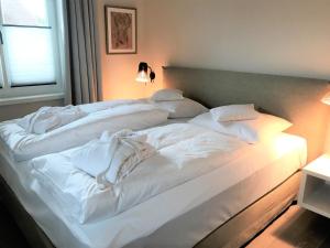 a large white bed with white sheets and pillows at Lerchenhof in Wenningstedt