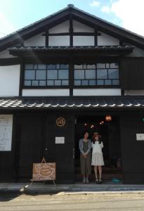 dwie osoby stojące w drzwiach budynku w obiekcie Akitsuki Kominka Ryokan You w mieście Asakura