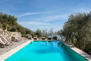 - une piscine d'eau bleue avec des chaises et des arbres dans l'établissement Eremo della Maddalena, à Monterosso al Mare