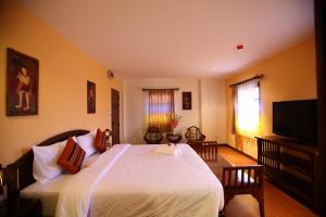 a bedroom with a large white bed and a flat screen tv at Chiang Mai Boutique House in Chiang Mai