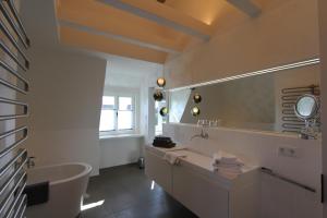 a bathroom with a tub and a sink and a mirror at Lerchenhof in Wenningstedt +16 photos