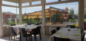 a restaurant with tables and chairs and a large window at Hotel Corallo in Fregene