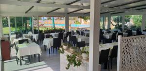 a restaurant with white tables and black chairs at Hotel Corallo in Fregene