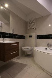 a bathroom with a tub and a toilet and a sink at Hotel Sunny in Poznań