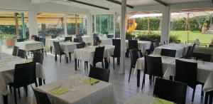 a restaurant with white tables and chairs and windows at Hotel Corallo in Fregene