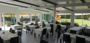 a restaurant with white tables and chairs and windows at Hotel Corallo in Fregene