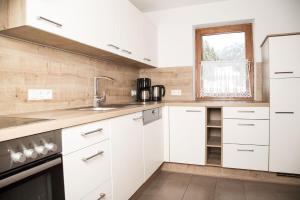 a kitchen with white cabinets and a sink and a window at Landhaus Maria in Neustift im Stubaital