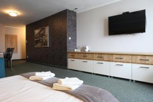 Hotel Sunny في بوزنان: غرفة نوم مع سرير وتلفزيون بشاشة مسطحة على الحائط