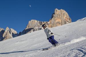 a person is skiing down a snow covered mountain at Camping Castelpietra in Fiera di Primiero