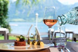 Una mesa con un plato de comida y una copa de vino. en Hotel Seevilla Wolfgangsee, en St. Wolfgang