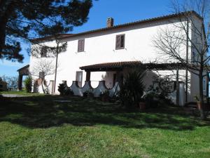 un grand bâtiment blanc avec une pelouse dans l'établissement Poggio Petrella, à Manciano