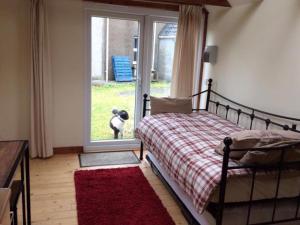 a bedroom with a bed and a window with a dog outside at George's House - 1 Leacklee in Manish