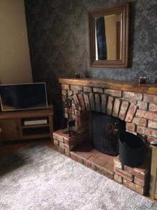 a living room with a brick fireplace and a mirror at George's House - 1 Leacklee in Manish