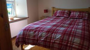 a bedroom with a bed with a plaid blanket at George's House - 1 Leacklee in Manish