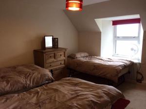 a bedroom with two beds and a dresser and a window at George's House - 1 Leacklee in Manish