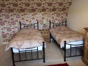 two twin beds in a room with floral wallpaper at George's House - 1 Leacklee in Manish