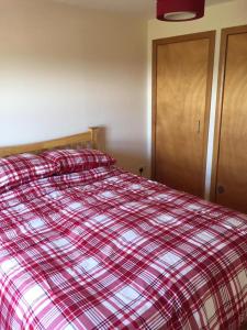 a bed with a red and white plaid blanket at George's House - 1 Leacklee in Manish