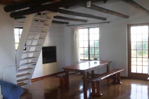a dining room with a table and a spiral staircase at Koensrust Sea Farm in Vermaaklikheid
