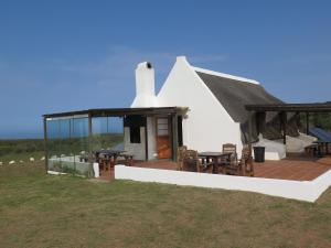 ein weißes Haus mit einer Terrasse mit Tischen und Stühlen in der Unterkunft Koensrust Sea Farm in Vermaaklikheid