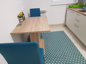 a kitchen with a wooden table and two blue chairs at Apartment Petra in Slatina
