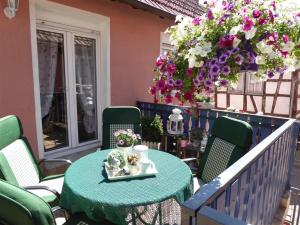 Ferienhaus Agnes في Ramberg: طاولة خضراء وكراسي على شرفة بها زهور