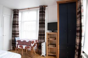 a bedroom with a bed and a table and a tv at Caledonian Studio Flats in London