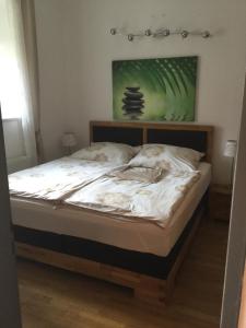 un letto con lenzuola bianche e un dipinto verde sul muro di Haus Ferdinand a Fernitz