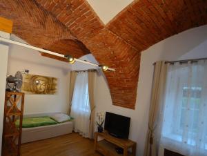 een kamer met een bakstenen plafond, een bed en een televisie bij Haus Ferdinand in Fernitz