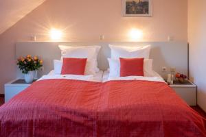 a bedroom with a large red bed with two red pillows at Hotel zur Therme in Erwitte