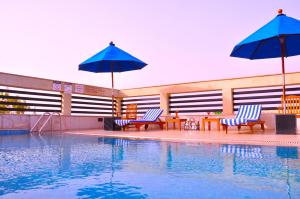a swimming pool with two chairs and umbrellas next to a pool at Fortune Sector 27, Noida - Member ITC Hotels' Group in Noida